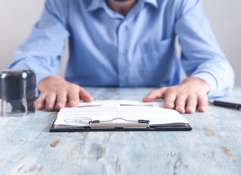 Businessman sitting in office. Stamp, document and pen on the desk.